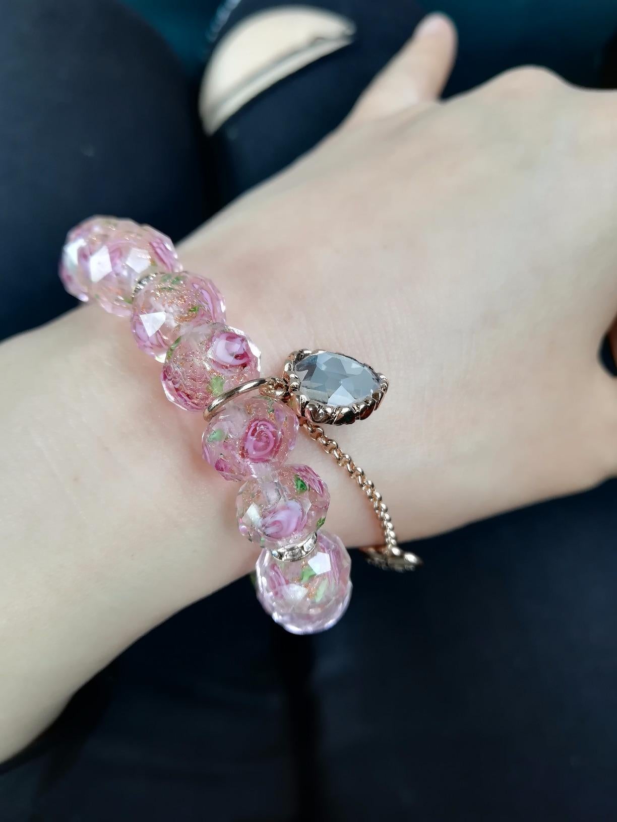Reviewer wearing pink beaded bracelet with rose accents and a gold and diamond gem charm