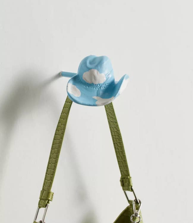 A purse hanging from a cloud print cowboy hat hook
