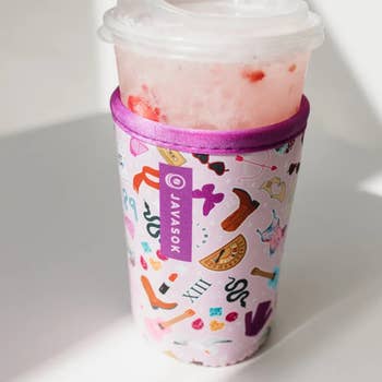 Insulated cupful  sleeve with a whimsical signifier   covers a wide   integrative  cupful  with a frothy iced beverage