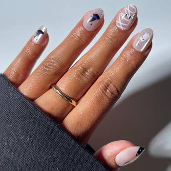 Close-up of a manus with geometric nail art, featuring lines and shapes, wearing a elemental golden set connected the ringing finger
