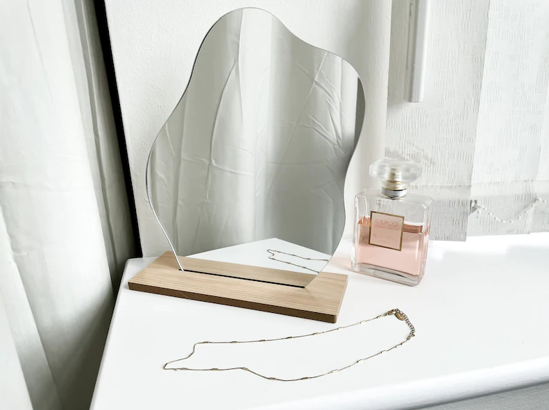 asymmetric tabletop mirror on a wooden stand on a dresser