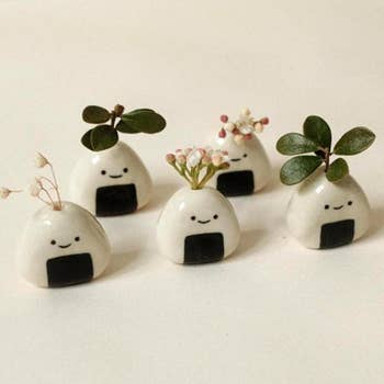 Five small, round ceramic planters with smiling faces, each holding a plant, ideal for decorative indoor shopping