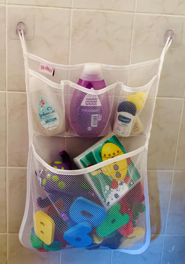 reviewer's bath organizer with  mesh pockets filled with toys and other items while attached to shower wall via suction cups