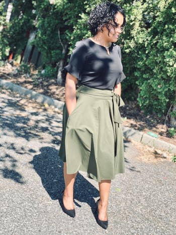 Reviewer is wearing a black top and a green midi skater skirt