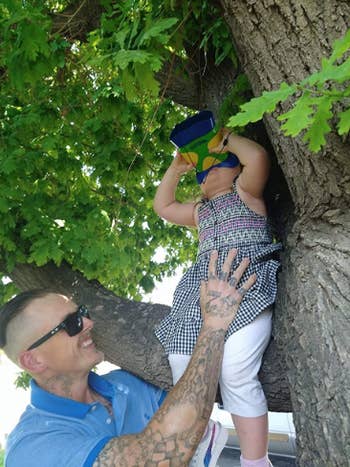reviewer holding child in tree while they use binoculars 
