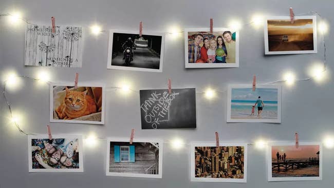 White wall with string of lights with clips and photos attached