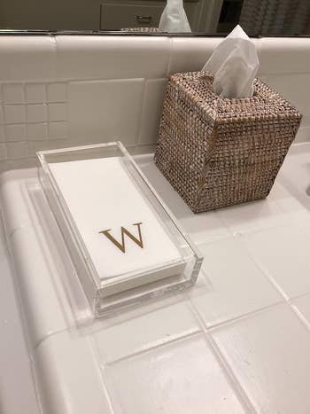 Tissue holder and monogrammed 'W' impermanent  towels connected  a bath  antagonistic  suggest   a interaction   of elegance and personalization for location  decor