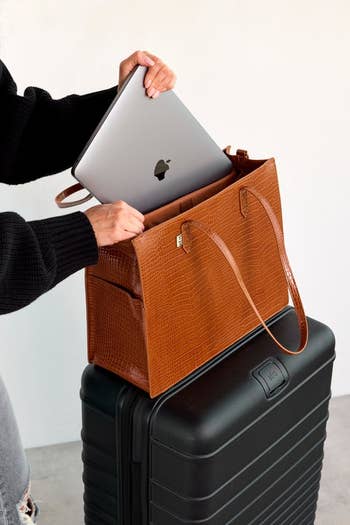 The model pulling out a laptop from the bag thats mounted on a suitcase