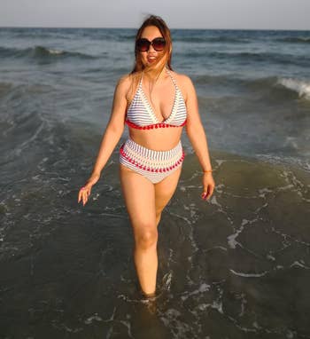 another reviewer wearing a white and blue striped bikini with red tassels 