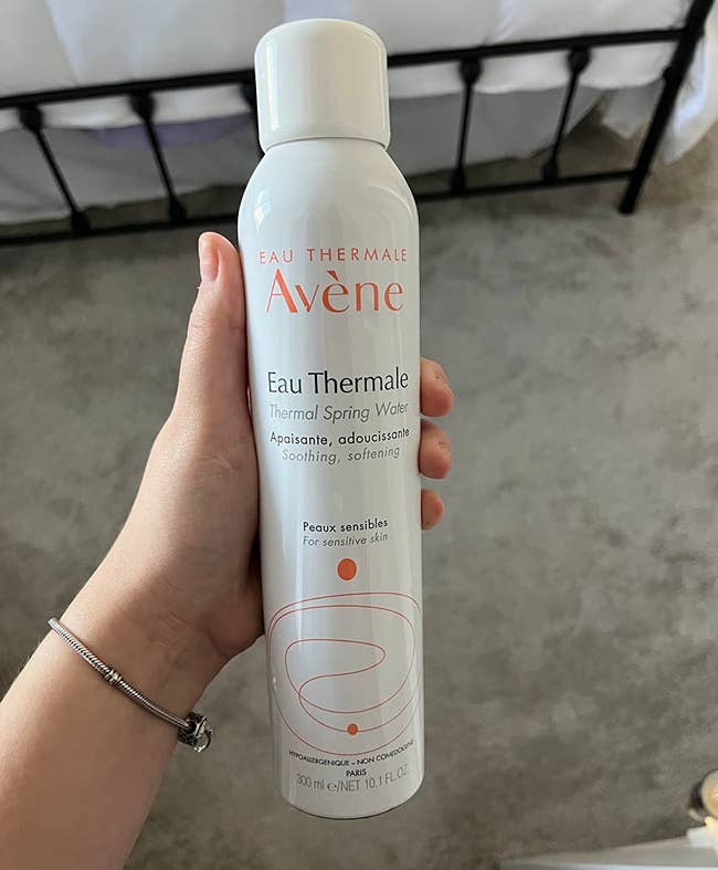 Person holding a 300ml tin of Avène Eau Thermale Thermal Spring Water, labeled for soothing and softening delicate skin