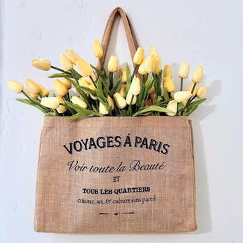 Tote container  with French text, filled with yellowish  tulips. The container  reads 