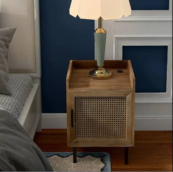 lifestyle photo of the wooden nightstand with a lamp on it