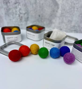 rainbow assortment of felted balls on display in front of metal tins
