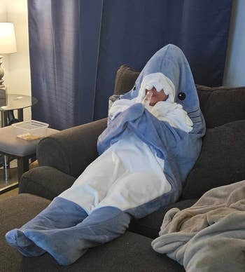Person in a shark costume lounges on a couch