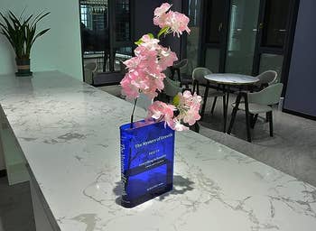 The blue vase with pink flowers on a marble countertop