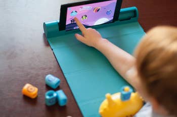 A child touching their tablet while playing the math game