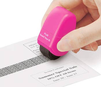 hand using the pink roller to cover up personal information on an envelope