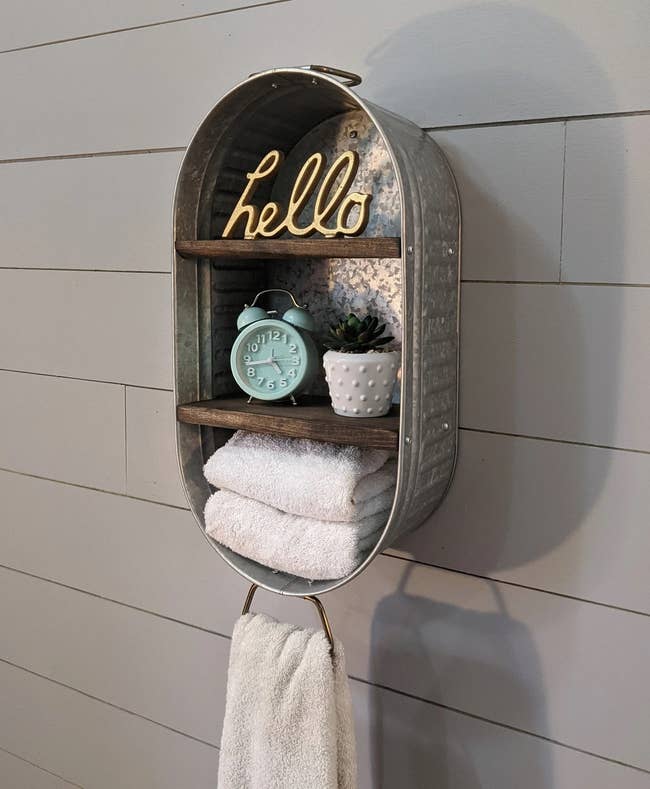 the galvanized wash tub shelving unit mounted on a wall with towels and other decor in it