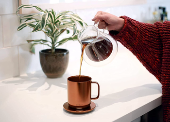 person pouring coffee into copper ember mug