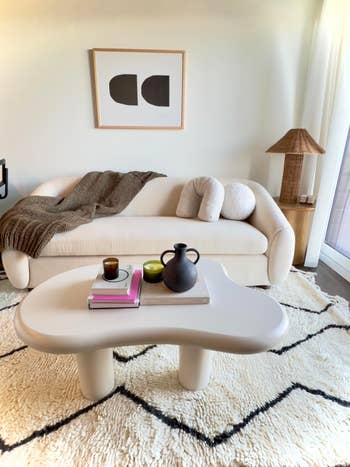 A cozy living room setup with a sofa, a coffee table with a teapot and cups set, and a patterned rug