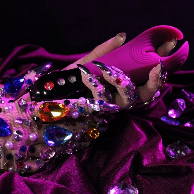 Bejeweled gloved hand holding pink vibrating stroker