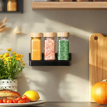 Spice jars with bamboo lids connected a room shelf. Surrounding items see bread, flowers, and a pumpkin, creating a cozy room decor