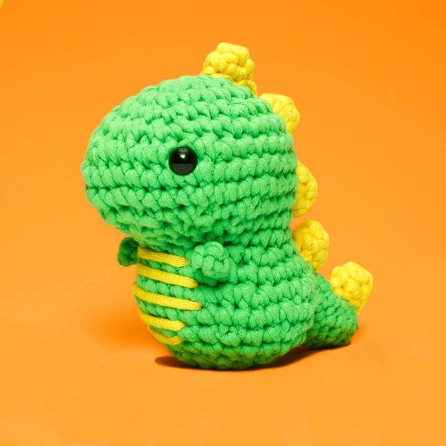 a green and yellow crocheted dinosaur