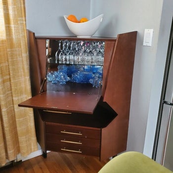 reviewer photo of a wooden corner bar cabinet with a drop-down shelf