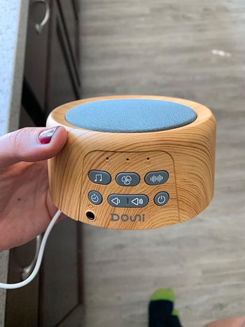 reviewer pic of same white noise machine in reviewer's hand