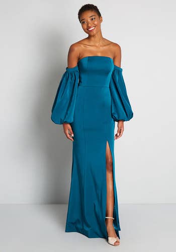 model in teal strapless high slit gown with long off shoulder voluminous sleeves