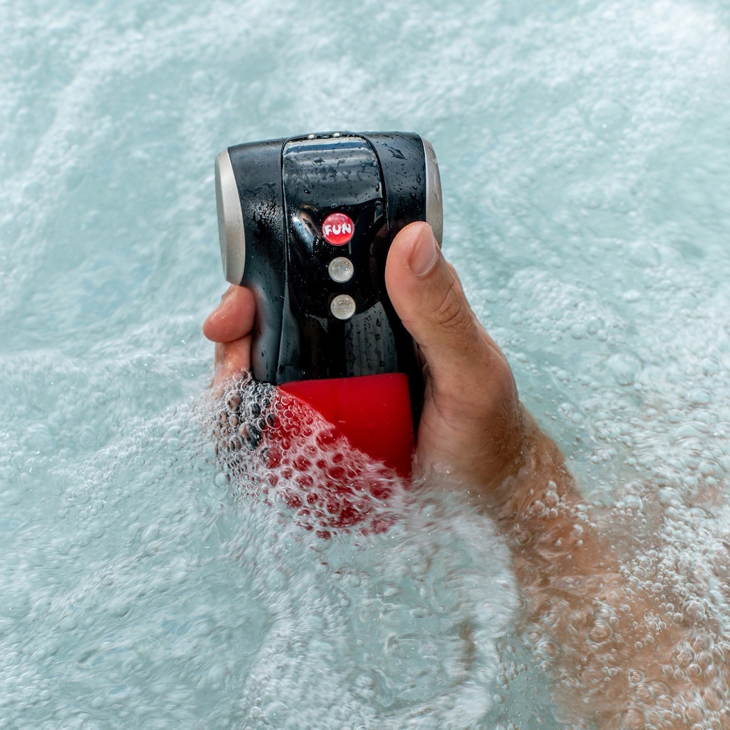 Model holding red penis vibrator in water