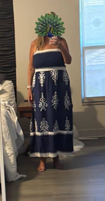 Person successful a strapless maxi formal with intricate patterns stands successful a bedroom, posing successful beforehand of a mirror