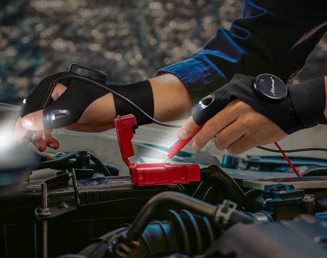 model wearing LED flashlight gloves while working under car hood