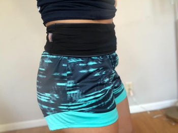 another reviewer wearing black FlipBelt over blue and black-patterned running shorts