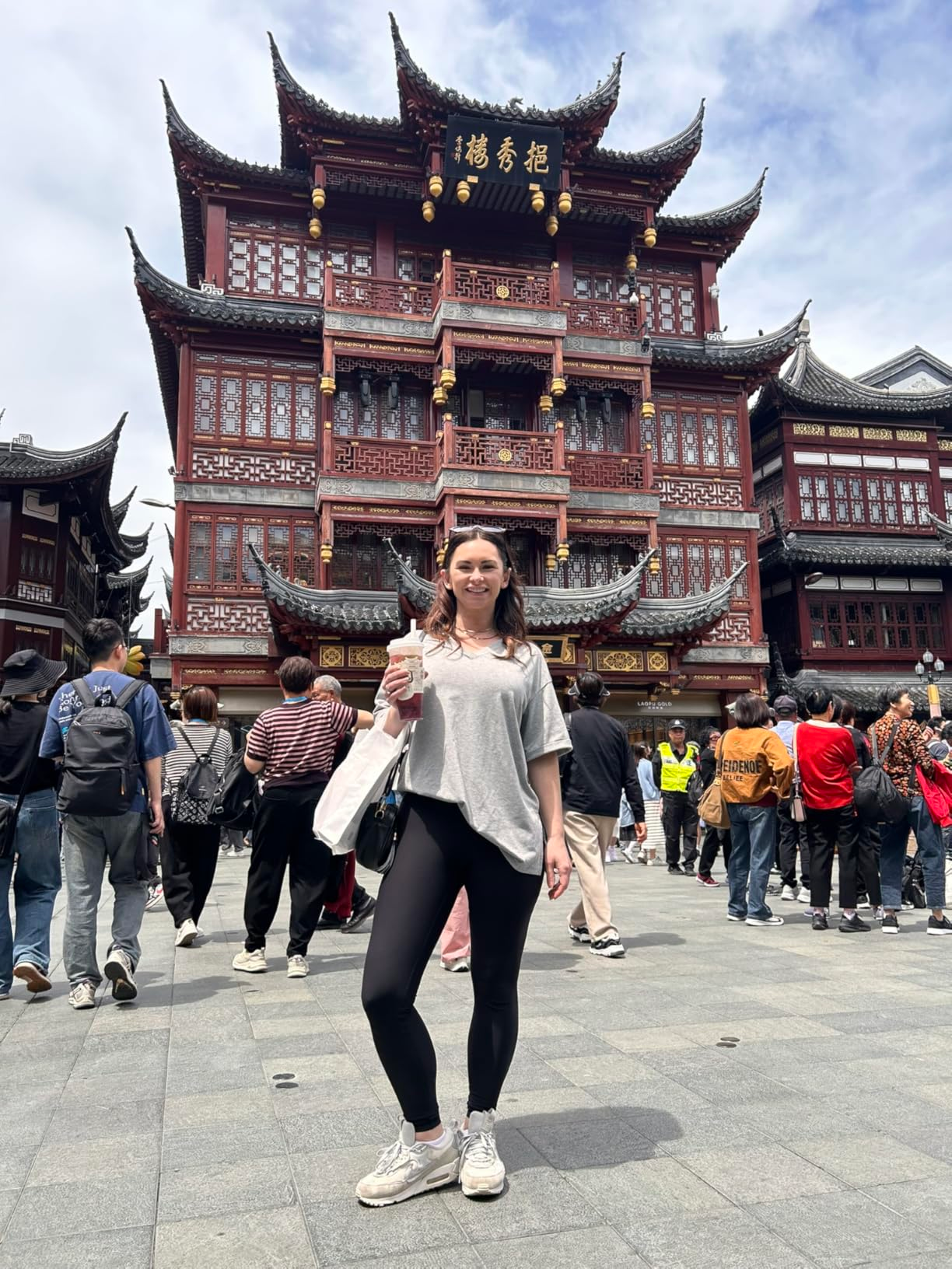 Person successful  casual apparel  holding a drink, lasting  successful  beforehand   of a accepted   Asian architectural gathering  with a engaged  assemblage  surrounding