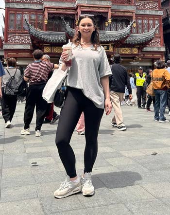 Person successful casual apparel holding a drink, lasting successful beforehand of a accepted Asian architectural gathering with a engaged assemblage surrounding
