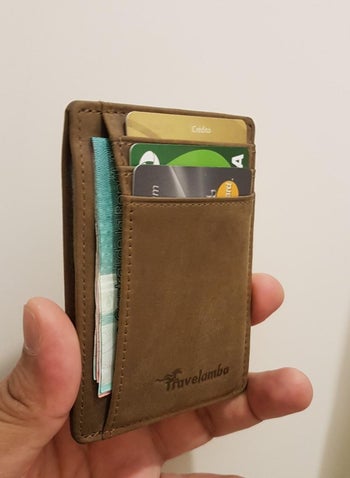 reviewer holding slim brown wallet