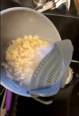 gif of reviewer draining water out of a bowl of pasta using the gray snap n' strain