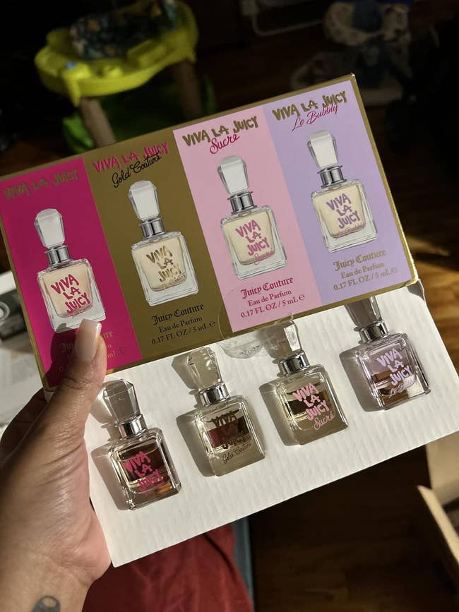 A manus holds a Juicy Couture Viva La Juicy perfume acquisition acceptable with 5 mini bottles, including Gold Couture and Le Bubbly scents. Ideal for gifting