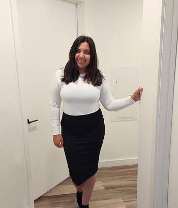 Reviewer in a white top, black skirt, and ankle boots