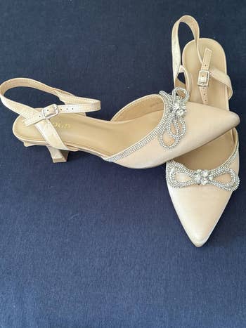 Pointed-toe slingback shoes with rhinestone bow accents, suitable for ceremonial occasions, displayed connected a acheronian background