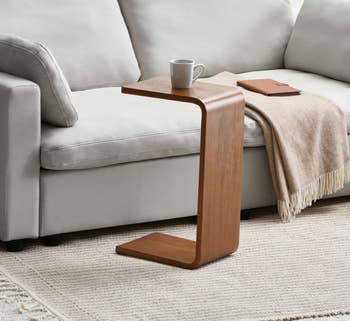 Modern surviving country with a sofa, cozy blanket, woody C-shaped array holding a mug, and a woven handbasket connected a textured rug