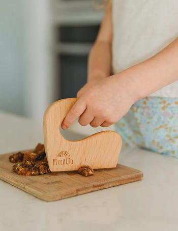 a closeup of a child using mini wood cutter to chop nuts