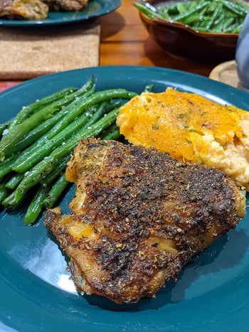 reviewer photo of a chicken thigh seasoned with the spice mix on a plate with some sides