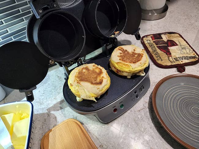 A reviewer's sandwich maker with two breakfast sandwiches on it