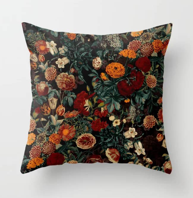 Black throw pillow with red, white, and orange flowers