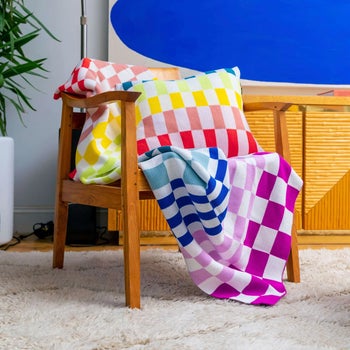 a rainbow checkered throw blanket draped over a chair with a matching throw pillow
