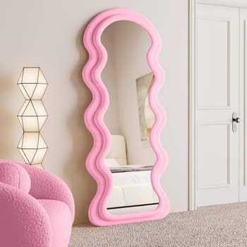 Wavy pink-framed full-length reflector  successful  a modern   country   with geometric lamp and plush chair