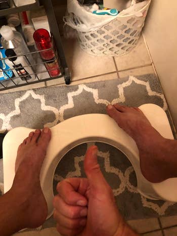Person utilizing a achromatic  footstool successful  a bathroom, with a thumbs-up motion  successful  the foreground. Various toiletries are disposable   successful  the background