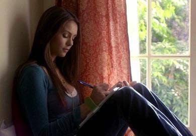 Elena writing in her diary by a window.